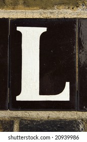 The Letter L From Tiled Street Sign On Brick Wall London England UK