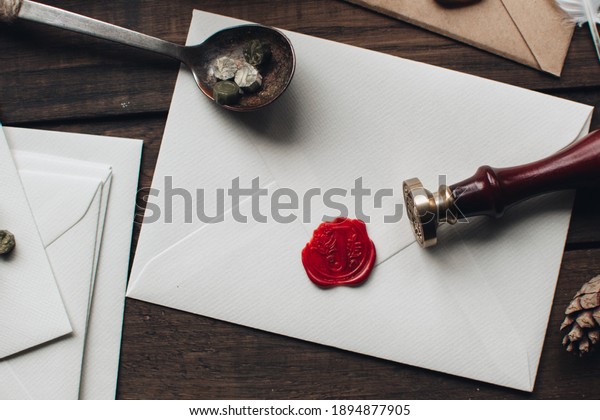 Letter seal with wax seal stamp on the wood\
table. Vintage notary stamp and sealed envelope. Post concept.\
Sealing wax. Wax seal. Dark academia style. Scandinavian hygge\
styled composition.