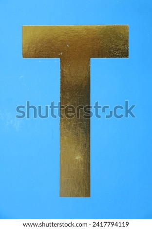 Letter T uppercase - golden color font on blue background, Close up