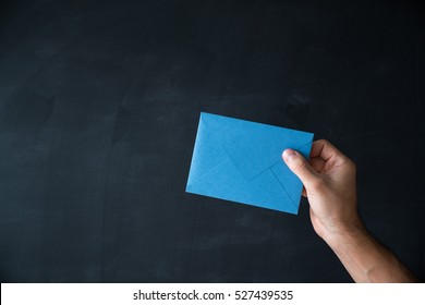 Letter For You. Hand Holding Blank Envelope Mock-up. Envelope Of Blue Color On A Black Background Close-up Hand.