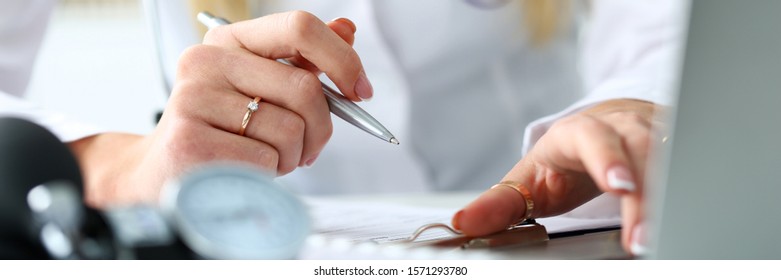 Letterbox view of GP working with computer pc holding silver pen closeup