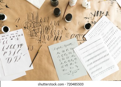 lettering, creation, work concept. paper with linens for training skills in calligraphy, black and white inks, brushes with thin tips and beautiful letters of english alphabeth written by designer