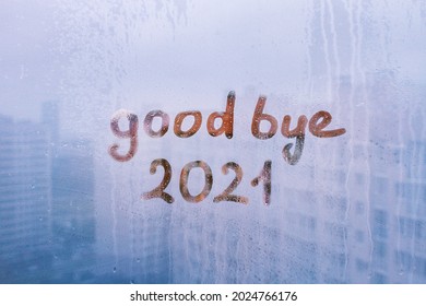 lettering good bye and numbers 2021 paint with finger with streaks of water on splashed by rain foggy glass on blue window