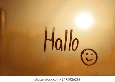 lettering Hallo in German is hello in English paint with finger with doodle smile on sunset foggy glass window - Powered by Shutterstock