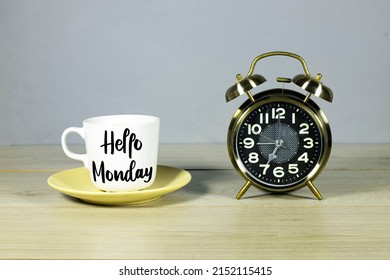 lettering hello Monday on cup of coffee with alarm clock showing 7 o'clock