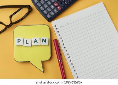 Lettering on Plan on the speech bubble with pen, notebook, calculator and eyeglasses.  Business and planning concept 