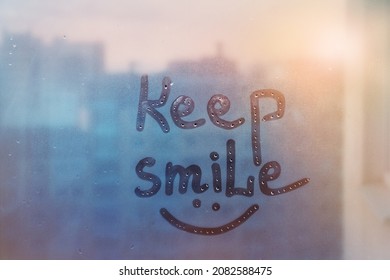 lettering text Keep smile and happy smile painted on window flooded with raindrops on blur blue glass background in city - Powered by Shutterstock