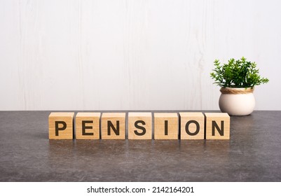 letters of the alphabet of pension on wooden cubes, the reflection of the inscription on the dark surface. a green plant on a white background