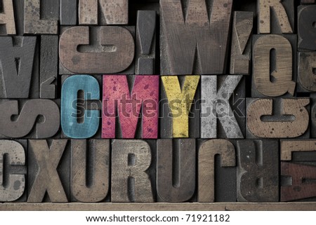 The letters CMYK written out in old letterpress blocks
