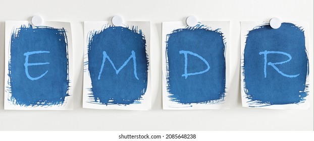 Letters EMDR written on blue paper on white board. Eye Movement Desensitization and Reprocessing psychotherapy treatment concept.