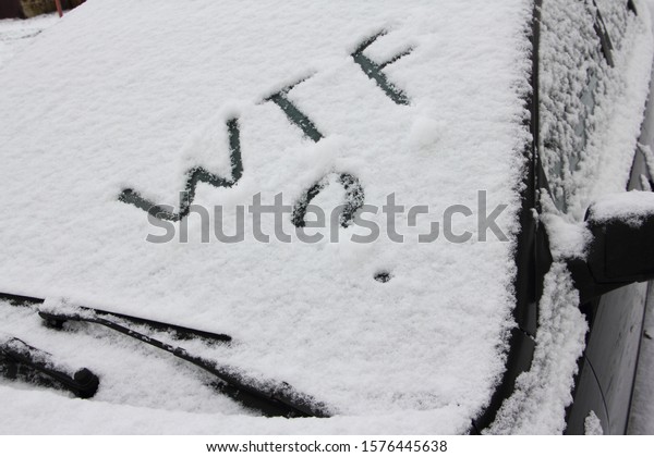 WTF? letters Inscription on snow car\
windglass with wiper blades close up, winter\
snowfall