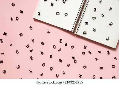 The letters are scattered in disarray on the blank pages of a notebook. English letters