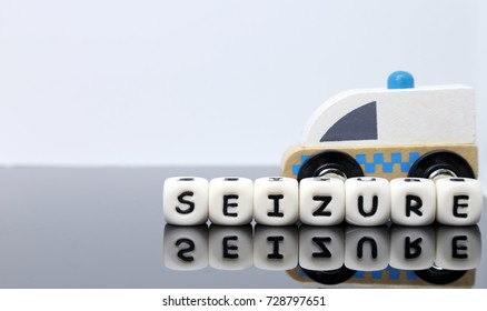 Letters Spelling A Word Seizure In Front Of A Model Ambulance On A Reflecting Background, Emergency, Rapid Response, Serious Medical Condition, Conceptual Idea