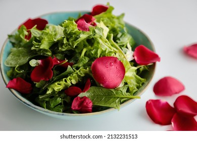 Lettuce salad with rose petals on a white background. rose petals are sprinkled on the edge of the plate. - Shutterstock ID 2132231513