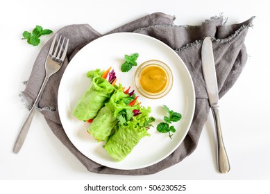 Lettuce vegetarian wraps or rolls stuffed with freshly chopped juicy vegetables and herbs, served with sauce and decorated with fresh mint leaves, view from above
