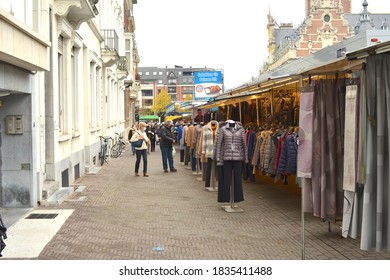 Leuven, Belgium - October 15, 2020: Square Herbert Hoover. Friday morning market in autumn. Food truck, customers waiting standing in front of a clothing stall. Dresses put on a mannequin doll.