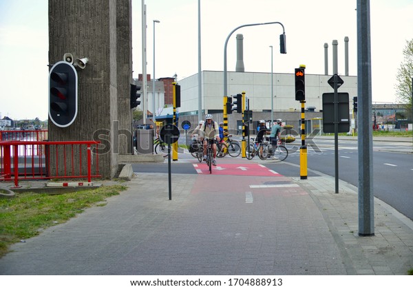 Leuven,\
Vlaams-Brabant, April 12, 2020: Ab-Inbev Stella Artois white\
houseJunction road. Traffic Lights, ship bridge, bicycle riders,\
foot path, river-canal\
Leuven-Mechelen.
