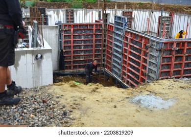 Leuven, Vlaams-Brabant, Belgium - September 17, 2022: Worker Attaching Chains To Materials For Lifting While Elevator Operator Waits With Joysticks