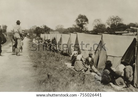Levee at Greenville, Mississippi, where African Americans sit by tents on uneven ground. The tents were supplied by the American Red Cross. With no established emergency response force, the U.S Congre [[stock_photo]] © 