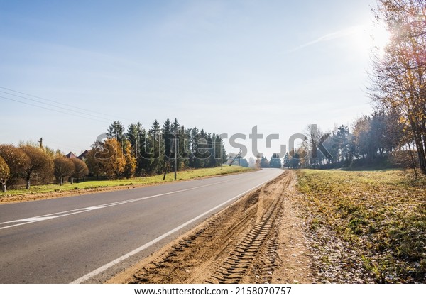 Level asphalt road. Empty turning highway under\
blue sky in sunny autumn day. European roadway landscape. Banner.\
Taxes and fees, toll road. Clean sandy roadside. Two-way traffic\
regulations. Safety.