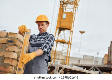 With level measuring tool. Construction worker in uniform and safety equipment have job on building. - Shutterstock ID 1898601646