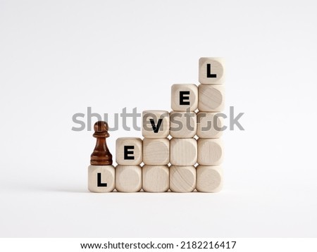 Level up or next level concept. Chess pawn is climbing the ladder of wooden cubes with the word level.