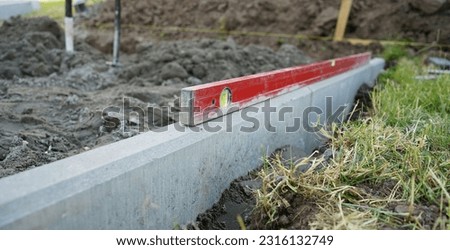 Level on the concrete kerb. Leveling on the construction site. Work zone. Measurement.