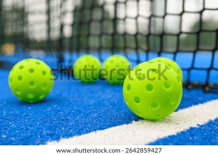level surface view of six pickleball balls near the net in a blue court