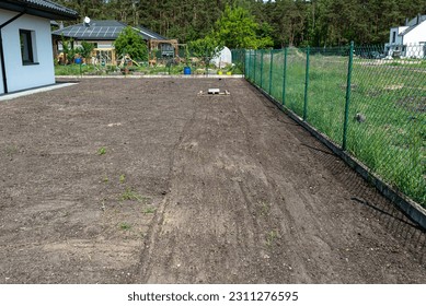 Leveling the chernozem in the yard with a pallet weighted with a concrete cube, preparing for sowing the lawn. - Shutterstock ID 2311276595