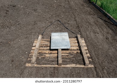 Leveling the chernozem in the yard with a pallet weighted with a concrete cube, preparing for sowing the lawn. - Shutterstock ID 2311280797