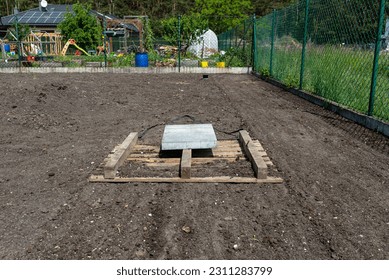 Leveling the chernozem in the yard with a pallet weighted with a concrete cube, preparing for sowing the lawn. - Shutterstock ID 2311283799