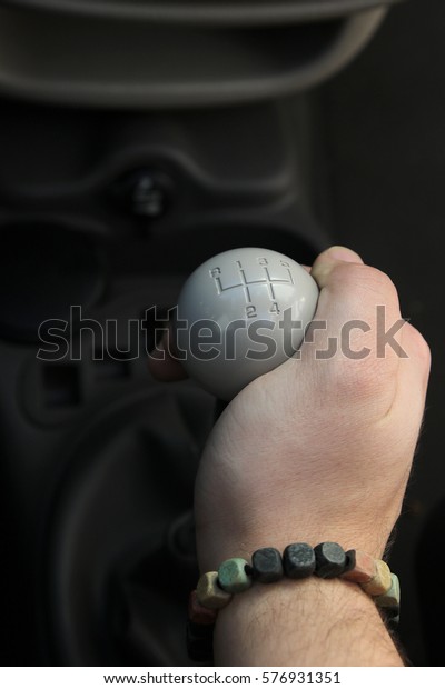 Lever manual old school five-speed gearbox and the\
man\'s hand that switches transmission. Gear-lever view from above.\
Handle a manual transmission in a blurry background. five speed\
manual gear stick