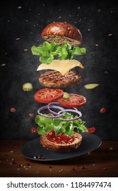 Levitating fresh ingredients of delicious warm burger on plate, grunge background
