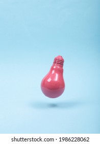 Levitating Pink Light Bulb On Blue Background. 3D Photo. Minimalistic Still Life. Creative Idea Layout. Concept Art