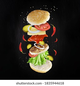 Levitating Spicy Cheeseburger Components On Dark Background. Sandwich Ingredients Floating In The Air: Red Peppers, Cucumbers, Cheese, Ketchup, Onion Rings, Cutlet, Tomatoes, Lettuce. Square Format.