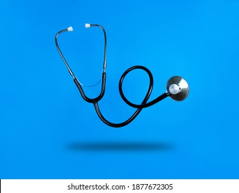 Levitating stethoscope on blue background and shadow under it. Stock photo.