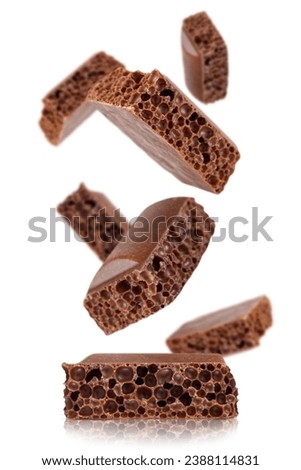 Levitation of cubes of milk porous chocolate isolated on a white background.