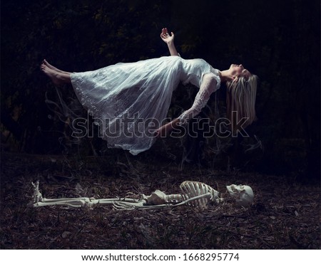 Levitation image of a woman rising from a skeleton on some dead leaves