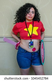 Lexington, KY US - March 11, 2018 - Lexington Comic & Toy Con Girl In Cosplay Costume Poses Against A Wall With A Shield And Sword, Curly Hair, Denim Shorts, Female, Teenager