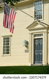 Lexington MA, USA — September 14, 2022: 18th Century Buckman Tavern At Lexington Green. The Minutemen Militia Gathering Place Of 1775. Betsy Ross Flag Of USA Flies Over Doorway.