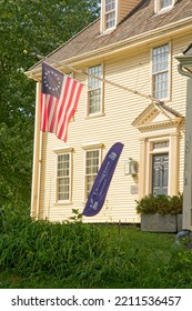 Lexington MA, USA — September 14, 2022: 18th Century Buckman Tavern At Lexington Green. The Minutemen Militia Gathering Place Of 1775. Betsy Ross Flag Of USA Flies Over Doorway.