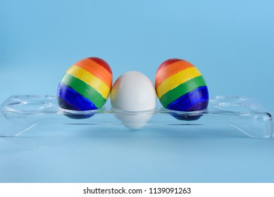 Lgbt Family. Eggs With Lgbt Flag Color And White Baby Egg On Blue Background. Creative Idea For Illustration Surrogacy Law, Right Homosexual Couple Adoption And Raising A Child.
