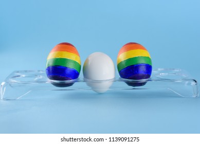 Lgbt Family. Eggs With Lgbt Flag Color And White Baby Egg On Blue Background. Creative Idea For Illustration Surrogacy Law, Right Homosexual Couple Adoption And Raising A Child.
