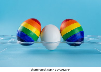 Lgbt Family. Eggs With Lgbt Flag Color And White Baby Egg On Blue Background. Creative Idea For Illustration Surrogacy Law, Right Homosexual Couple Adoption And Raising A Child.
