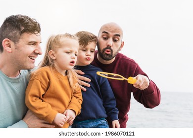 Lgbt Family Having Fun With Their Children At The Beach In Summer Vacation - Gay Dads And Sons Playing Together Outdoor - Main Focus On Right Man Face