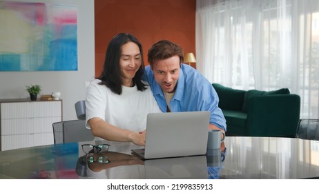 Lgbt Gays Feeling Happy Using Laptop At Home. Multiethnic Homosexual Male Couple Excited Looking At Computer Receiving Good News.