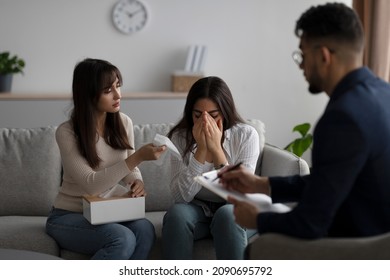 LGBT Lesbian Couple Consulting Phychologist. Middle Eastern Woman Crying, Her Gay Partner Comforting Her On Session With Marital Counselor At Clinic