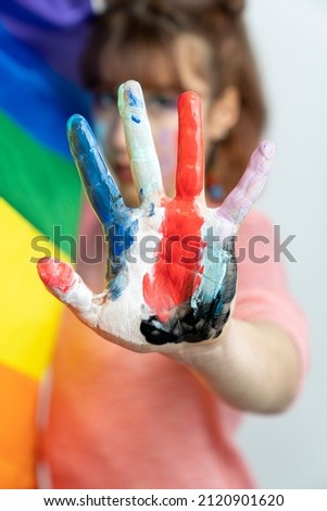 LGBT pride. Happy woman with lgbt flag. Happy woman showing hands painted in colorful paints 