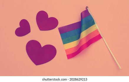 LGBT rainbow flag and hearts on pink background. Love has no gender. Tolerance, freedom