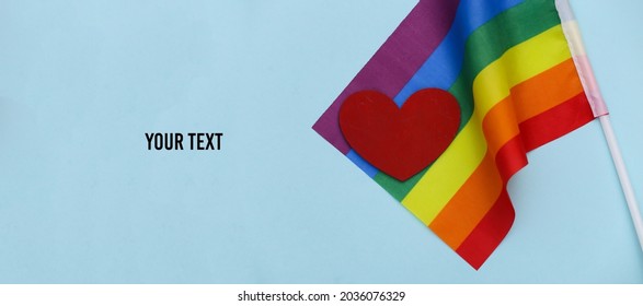 LGBT rainbow flag and red heart on blue background. Love has no gender. Tolerance, freedom. Copy space